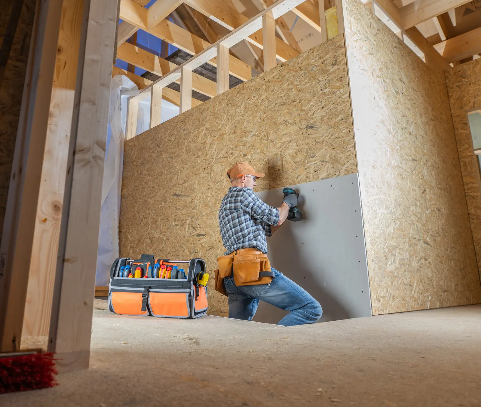 Worker installing drywall in a construction setting, showcasing tools and meticulous repair techniques, emphasizing quality drywall repair services by Elite Edge Drywall.