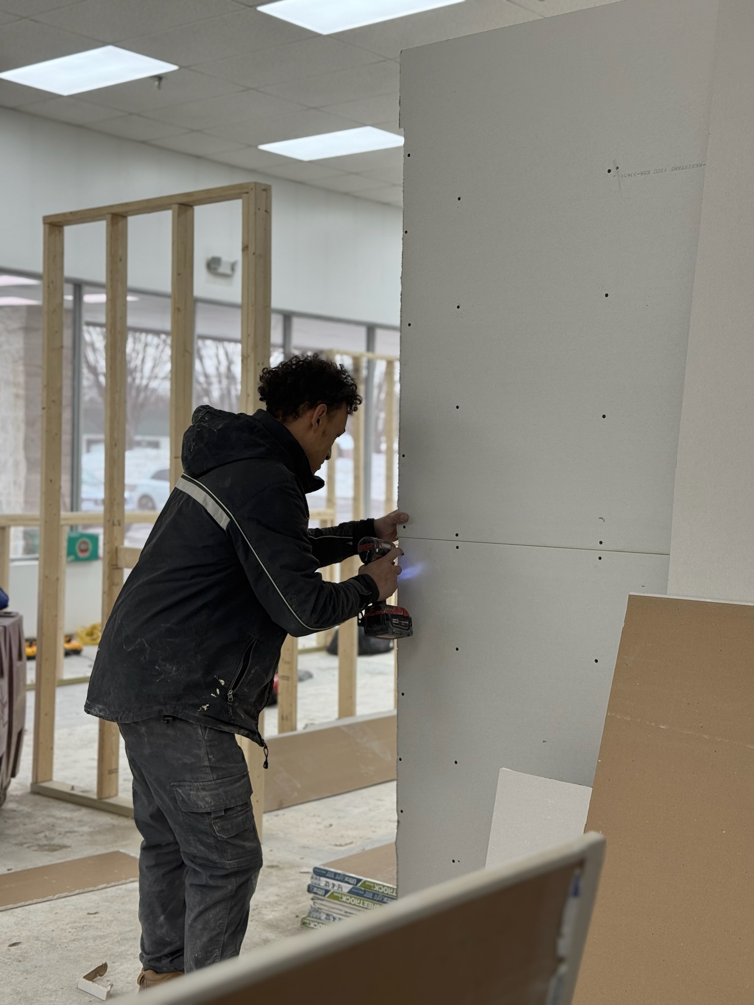 Worker installing drywall in a construction setting, demonstrating professional drywall repair techniques for seamless finishes.